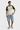 Pull ajouré Jargentine Blanc porté en pied par un homme, manches noires, avec short en jean brodé et baskets bleues