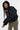 Blouson à capuche Eschott Noir porté par une mannequin femme en mouvement, capuche relevée, pantalon cargo kaki