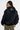 Blouson Eschott Noir porté de dos par une mannequin femme, capuche ornée d'un cœur brodé blanc