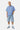 Chemise Jovenis Bleu portée en pied par un mannequin homme avec un short en jean brodé et baskets bleues