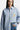 Chemise Juvaris Bleu rayée portée par une mannequin femme, poche poitrine à broderie jaune et étiquette Eleven sur la manche