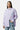 Chemise Juvaris Lilas rayée portée de face par une mannequin femme, main dans la poche du jean, broderie bleue sur la poche