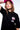 T-shirt Next Noir porté par une femme en casquette rose, plan rapproché sur le logo Eleven Karaoke Records rose et blanc