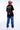 T-shirt Next Noir vu de dos, porté par une femme avec casquette rose et jean large, imprimé Karaoke Option No Snitch