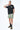 Maillot de bain Nibby Kaki porté par un homme avec t-shirt noir, main sur la nuque, de face en pied, mules marron