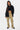 Pantalon cargo Suede Beige porté en pied par une mannequin femme avec chemise noire ouverte et haut court