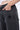Pantalon Beleo Noir délavé, gros plan sur la poche avant avec une fleur de lys noire, main dans la poche