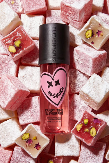 Brume parfumée Candy Time Eleven Paris, flacon rose au cœur smiley No Snitch posé sur des loukoums roses