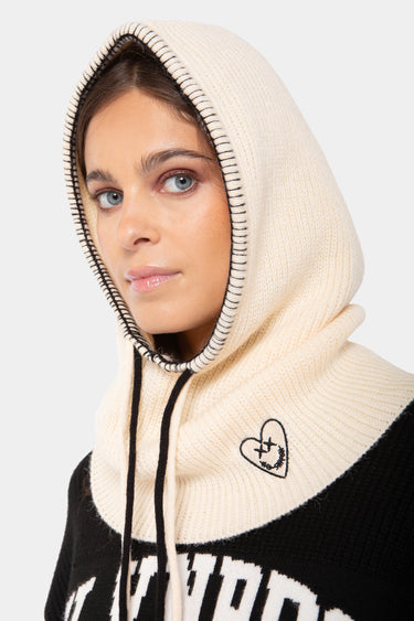 Accessoire Fanette Écru, cagoule en maille écrue à coutures noires portée par une femme, cœur smiley brodé