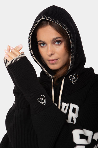 Cagoule et mitaines en maille Fraise Noir portées par une femme, coeur brodé et surpiqûres blanches sur la capuche