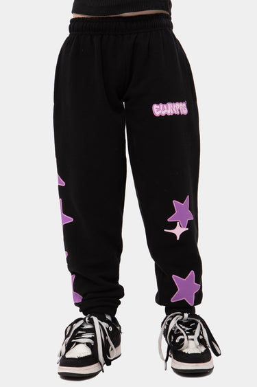 Jogging Jazzy Noir porté par un enfant, de face, étoiles violettes sur la jambe et inscription violette sur la cuisse