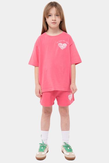 Short Jewel Rose porté avec le t-shirt rose assorti par une fille en pied, de face, coeur blanc sur la cuisse