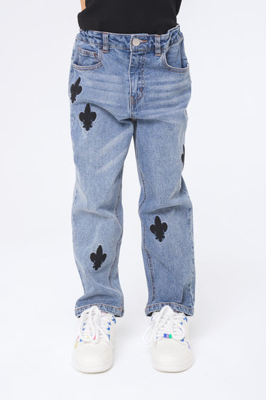 Jean Neleo Bleu jean porté de face par un enfant, patchs fleur de lys noirs sur les cuisses et le genou