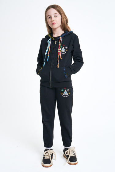 Sweat à capuche zippé Neliot Noir porté par une fille avec jogging noir assorti, mains dans les poches, de face