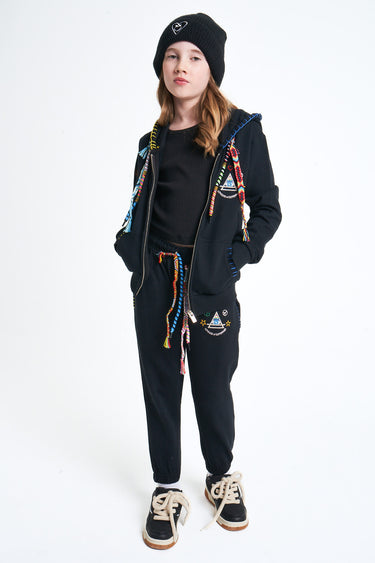 Pantalon Nika Noir porté par une fille avec sweat zippé noir assorti et bonnet, de face en pied