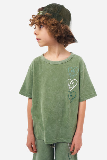T-shirt Perle Kaki porté par un garçon en casquette, vue de profil, trois coeurs souriants imprimés sur la poitrine