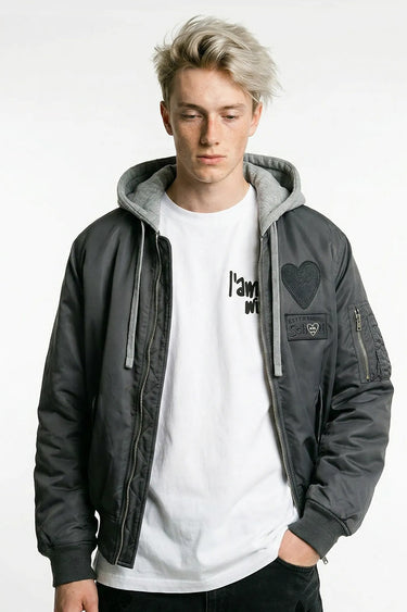 Blouson bomber Eschott Gris porté par un mannequin homme, de face, capuche grise, patch cœur noir et poche de manche zippée