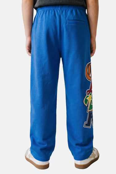 Jogging enfant Tenz Bleu porté par un enfant, de dos, poche arrière, patchs ELVN sur la jambe et baskets beiges