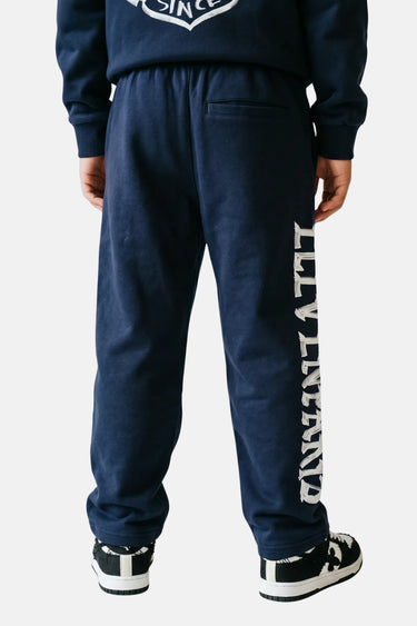 Jogging Tory Bleu Marine porté de dos par un enfant, poche arrière et inscription Eleven Paris le long de la jambe