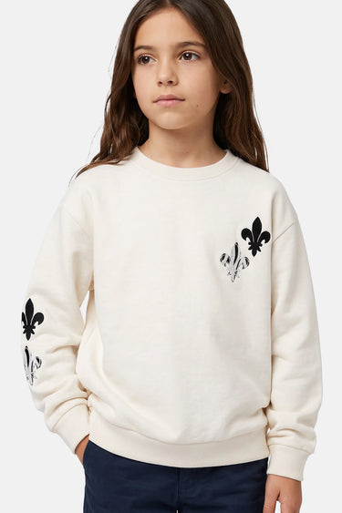 Sweat col rond Touli Écru en plan rapproché porté par une fille, fleurs de lys noires sur la poitrine et la manche