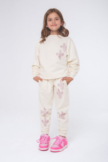Jogging Elena Écru porté par une fille de face, motifs fleurs de lys roses, avec baskets roses